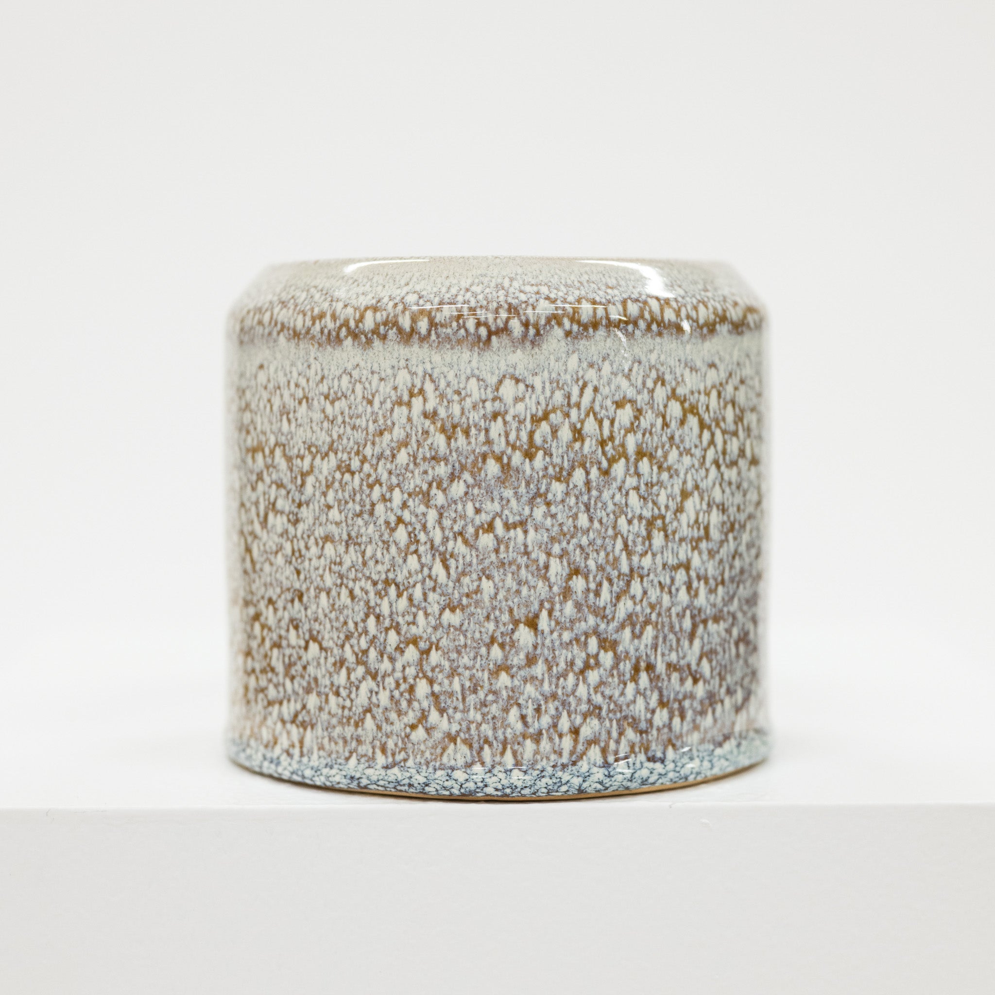 Speckled ceramic jar on a white background