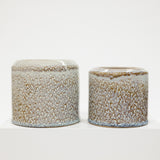 Two ceramic pots with brown and white 
textured surface on a white background