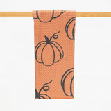 microfiber kitchen towel in burnt orange color with a pattern of repeated pumpkin outlines in black.