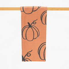 microfiber kitchen towel in burnt orange color with a pattern of repeated pumpkin outlines in black.
