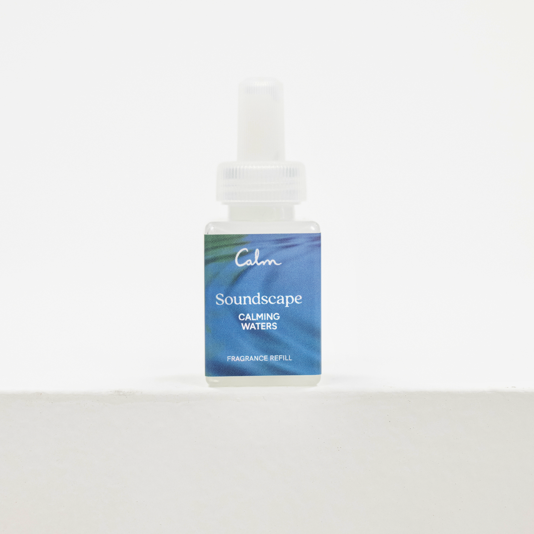 A small Pura fragrance refill bottle labeled 'Calm Soundscape Calming Waters Fragrance Refill' with a blue and green label, standing on a white surface against a white background.