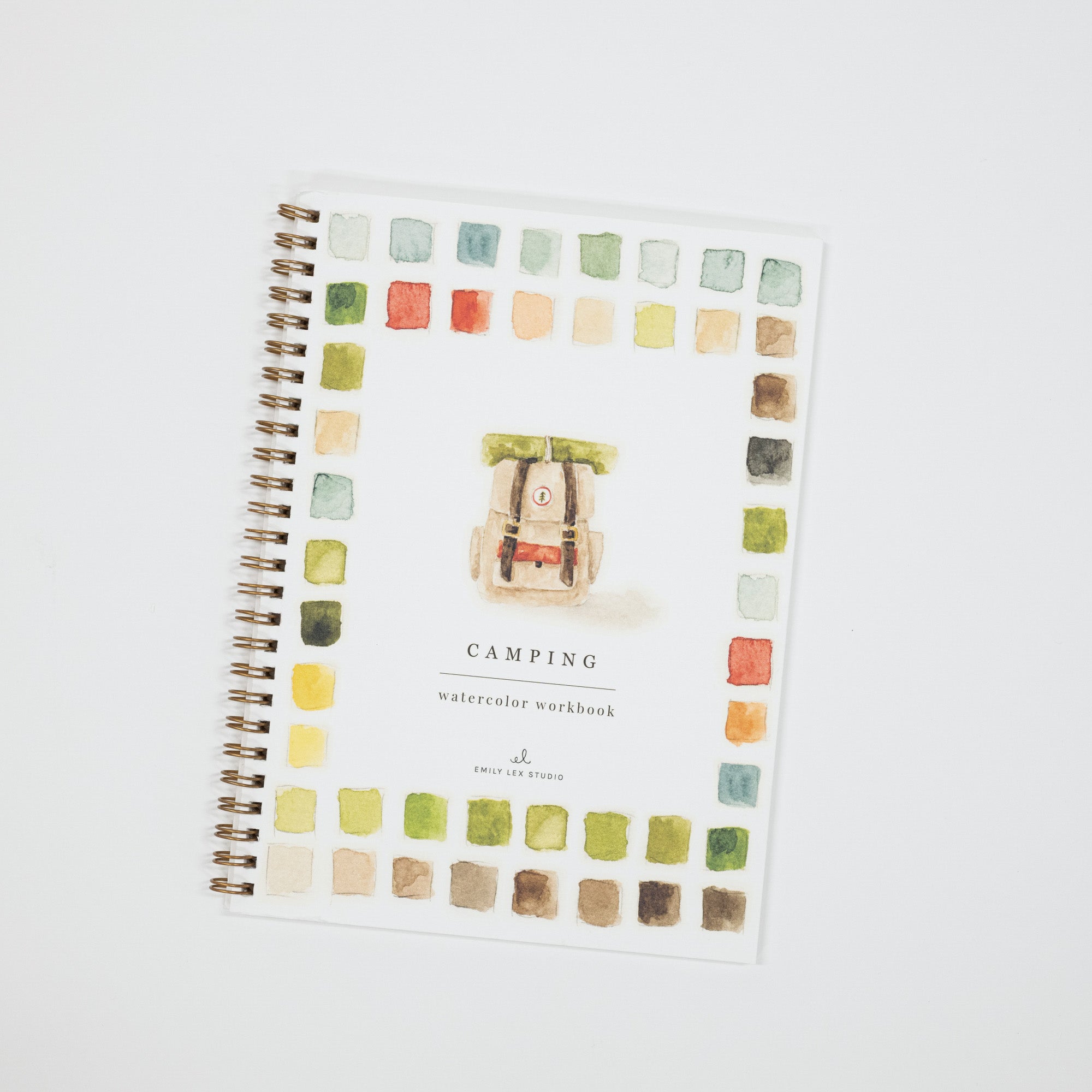A spiral-bound watercolor painting workbook titled 'CAMPING' on a clean white background. The cover features a central illustration of a vintage camping car surrounded by a border of small watercolor paint swatches in various earthy tones.