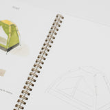 An open spiral notebook showing a tent color palette page with a green and yellow tent illustration, small color swatches, and a line drawing of the tent on white pages.