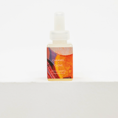 A small bottle of Becki Owens Caramel + Clove fragrance oil with a white dropper cap, set against a clean white background. Fall fragrance for Pura.