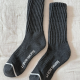 Pair of gray socks with 'Lebon Shoppe' branding on a textured beige surface