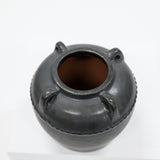Black ceramic jar with three small handles on a white background