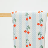 Towel with cherry pattern hanging on a wooden rack against a white background