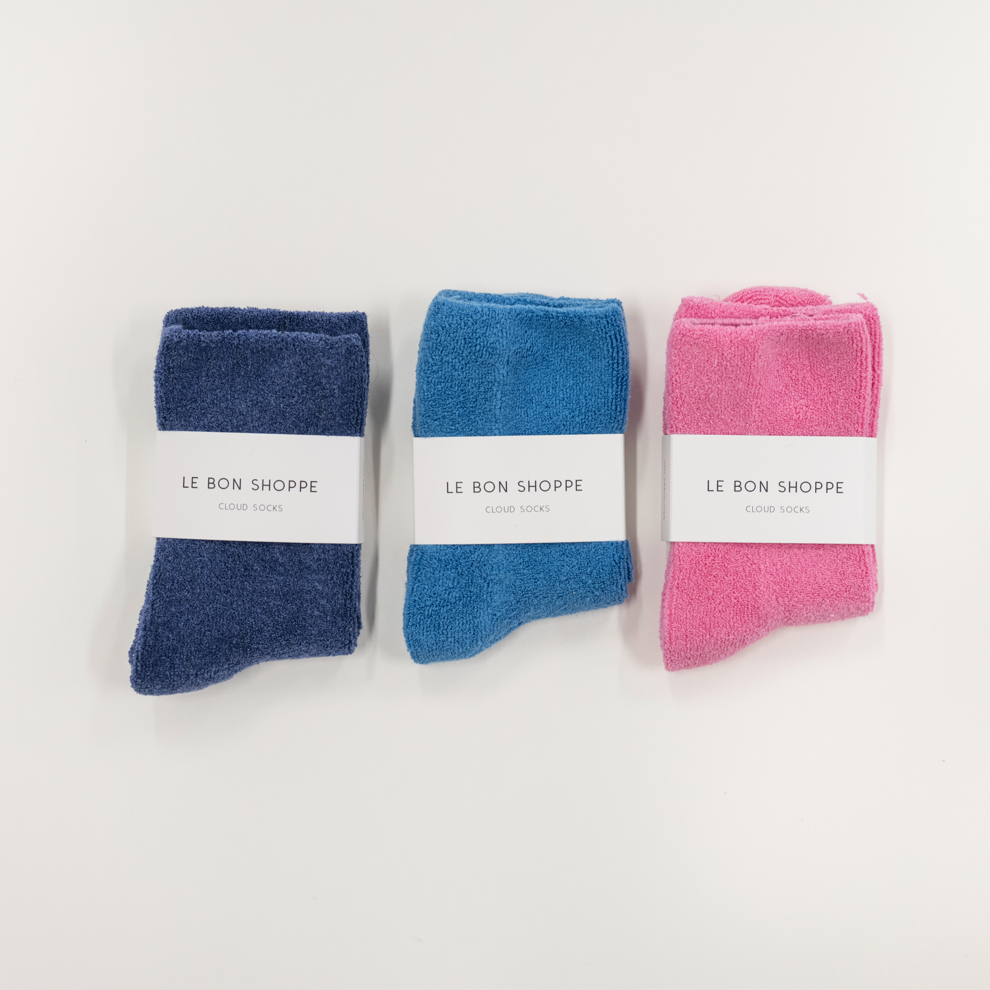 Three pairs of cloud socks in blue, pink, and navy with 'Le Bon Shoppe' labels on a white background.