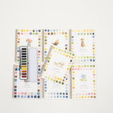 a collection of watercolor workbooks by Emily Lex and a watercolor paint palette 