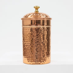 Copper jar with a textured surface and gold lid on a white background