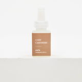 A small rectangular fragrance refill bottle with a white dropper cap and a tan label reading 'COZY CASHMERE' and 'pura. FRAGRANCE REFILL', centered on a clean white background. Fall scent for Pura.