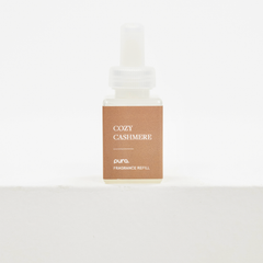 A small rectangular fragrance refill bottle with a white dropper cap and a tan label reading 'COZY CASHMERE' and 'pura. FRAGRANCE REFILL', centered on a clean white background. Fall scent for Pura.