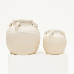 Two cream-colored ceramic jars with handles on a white background