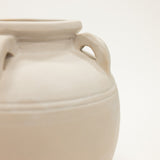 Beige ceramic jar with handles on a light beige background