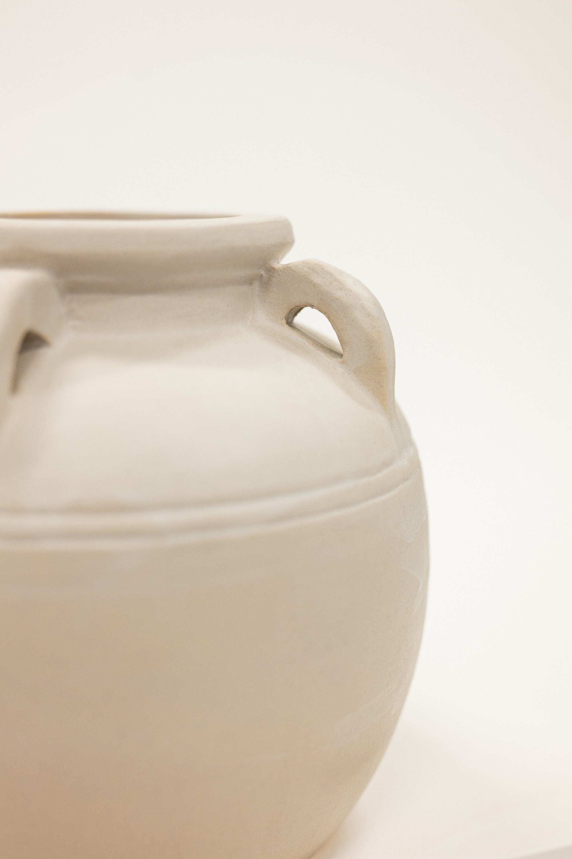 Beige ceramic jar with handles on a light beige background