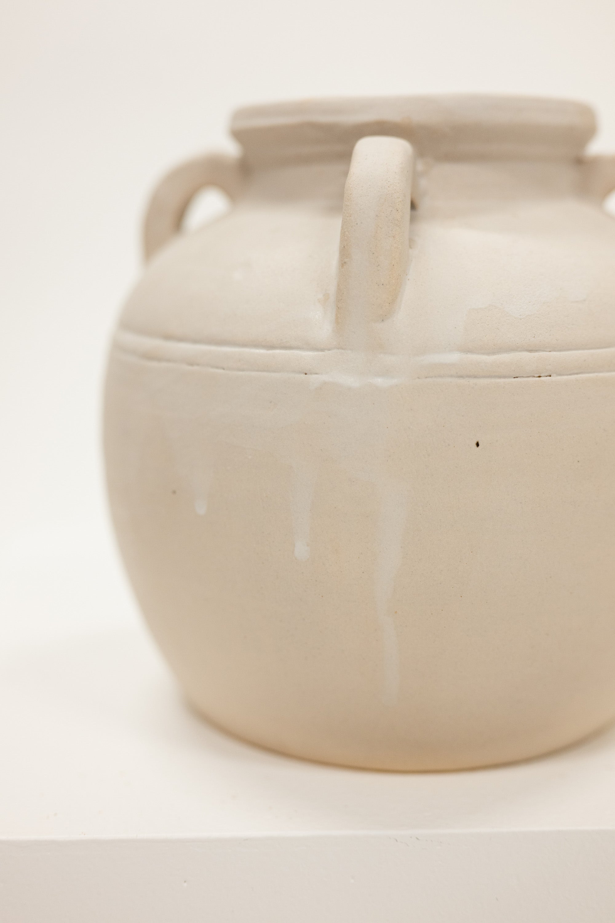 Beige ceramic jar with handles on a white background