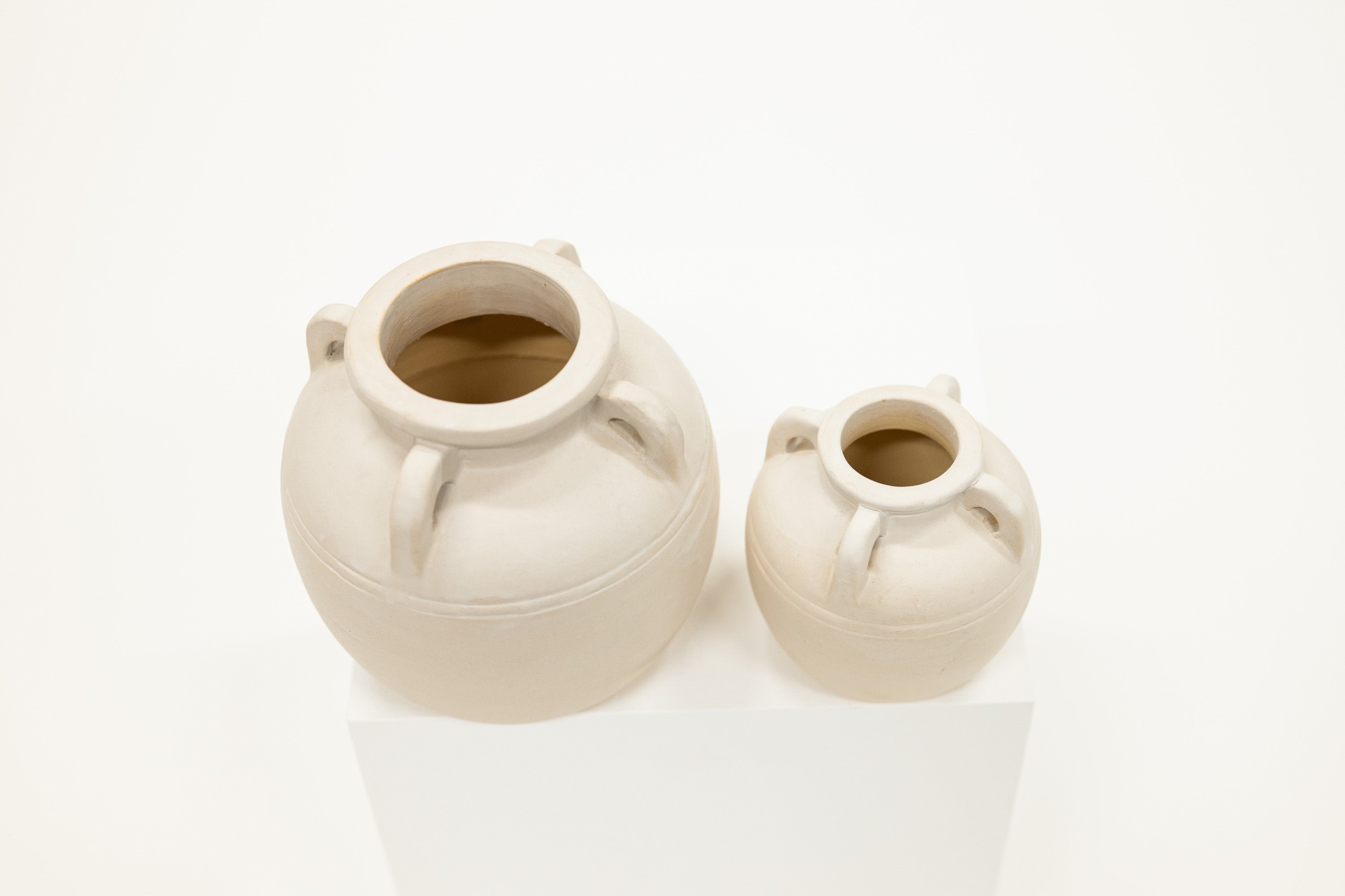 Two ceramic vases on a white surface with a white background