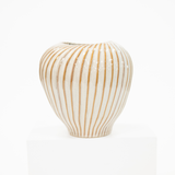 A ribbed ceramic vase with a glossy white glaze and vertical tan stripes, displayed on a white pedestal against a white background.