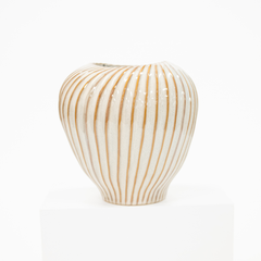 A ribbed ceramic vase with a glossy white glaze and vertical tan stripes, displayed on a white pedestal against a white background.