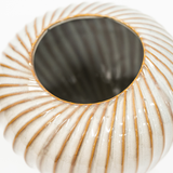 A close-up of a ribbed ceramic planter or vase with a glossy off-white glaze and warm brown edging, shown against a plain white background.