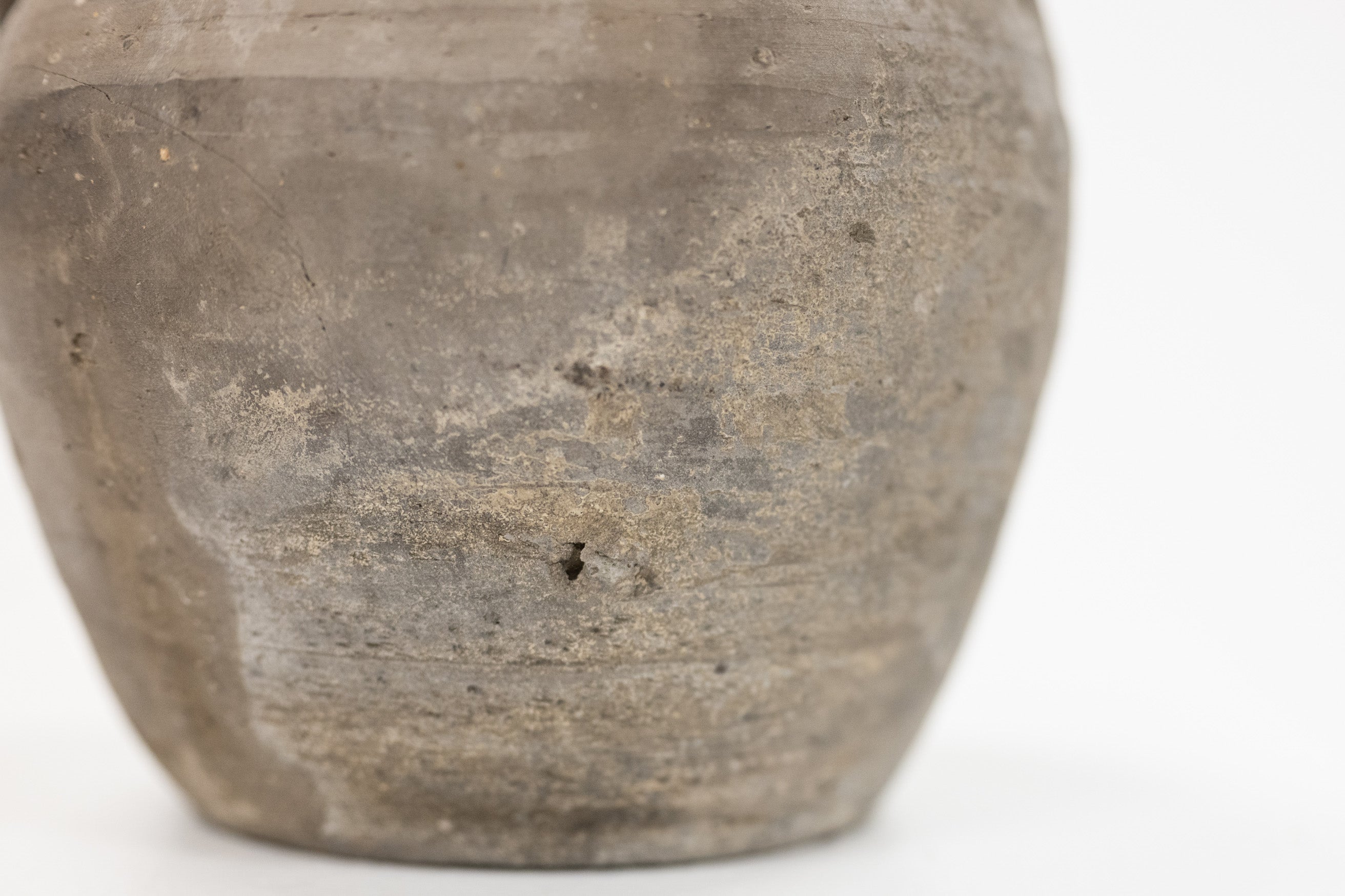 Close-up of a rustic, textured gray cumin pot on a clean white background.