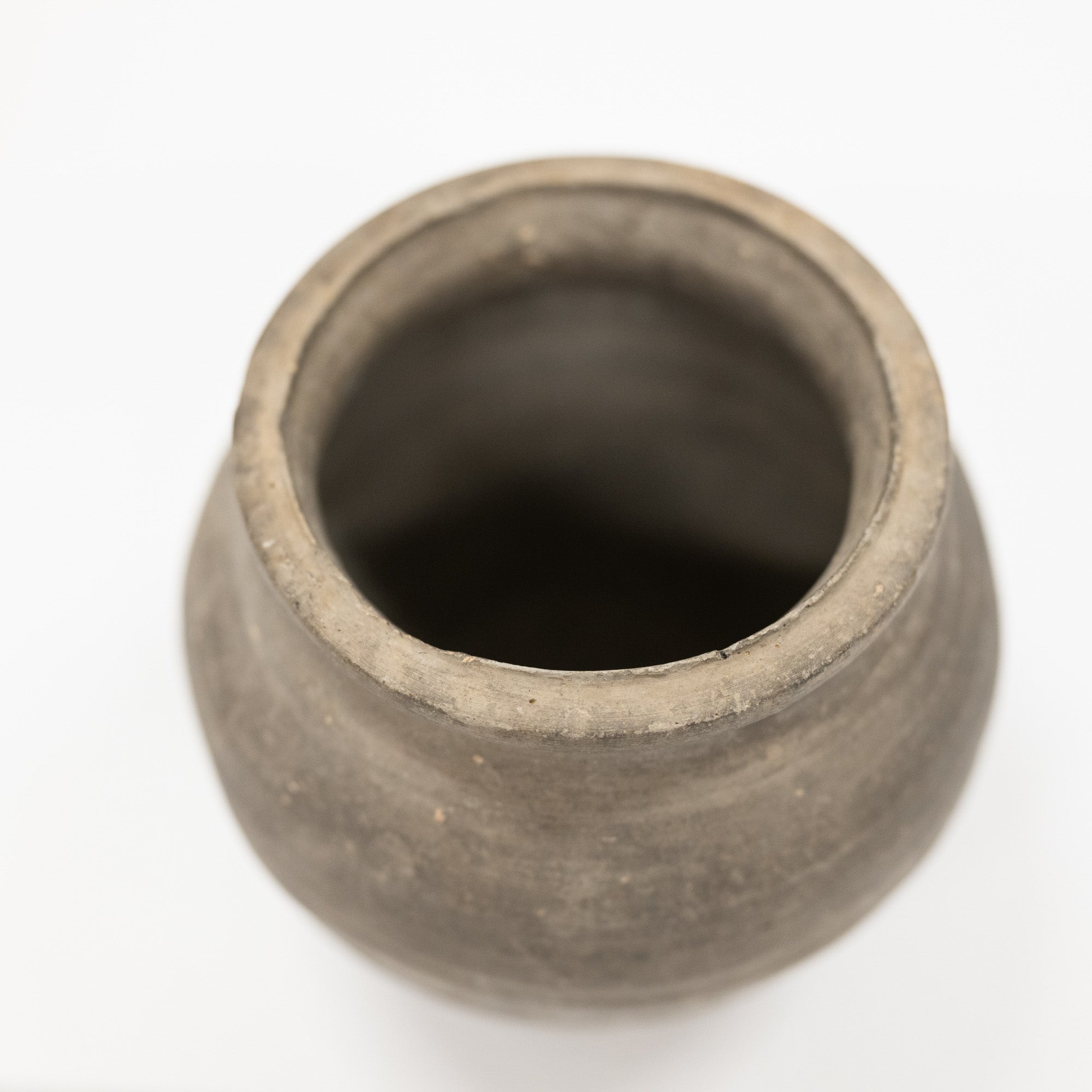 A small round clay pot with a wide, slightly flared rim, shown from a top-down perspective on a plain white background.