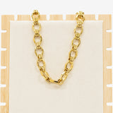 Gold chain necklace on a wooden stand with a white background
