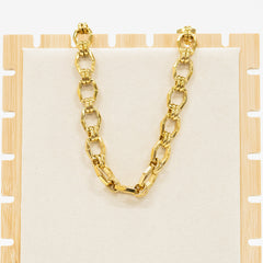 Gold chain necklace on a wooden stand with a white background