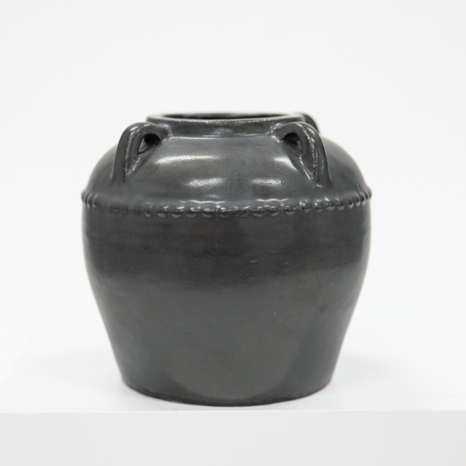 Black ceramic vase with handles on a white background