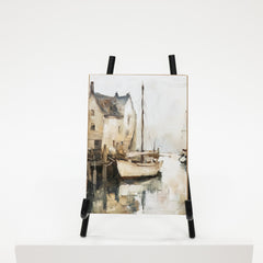 Art print of a coastal scene with a sailboat on an easel against a white background