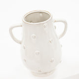 A white ceramic pitcher with two side handles and a textured, dimpled surface, photographed against a seamless white background.
