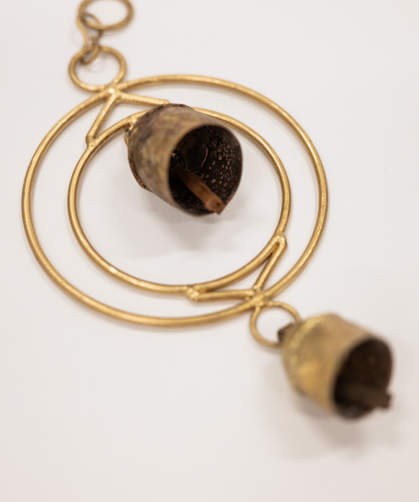 Gold circular pendant with chimes on a white background
