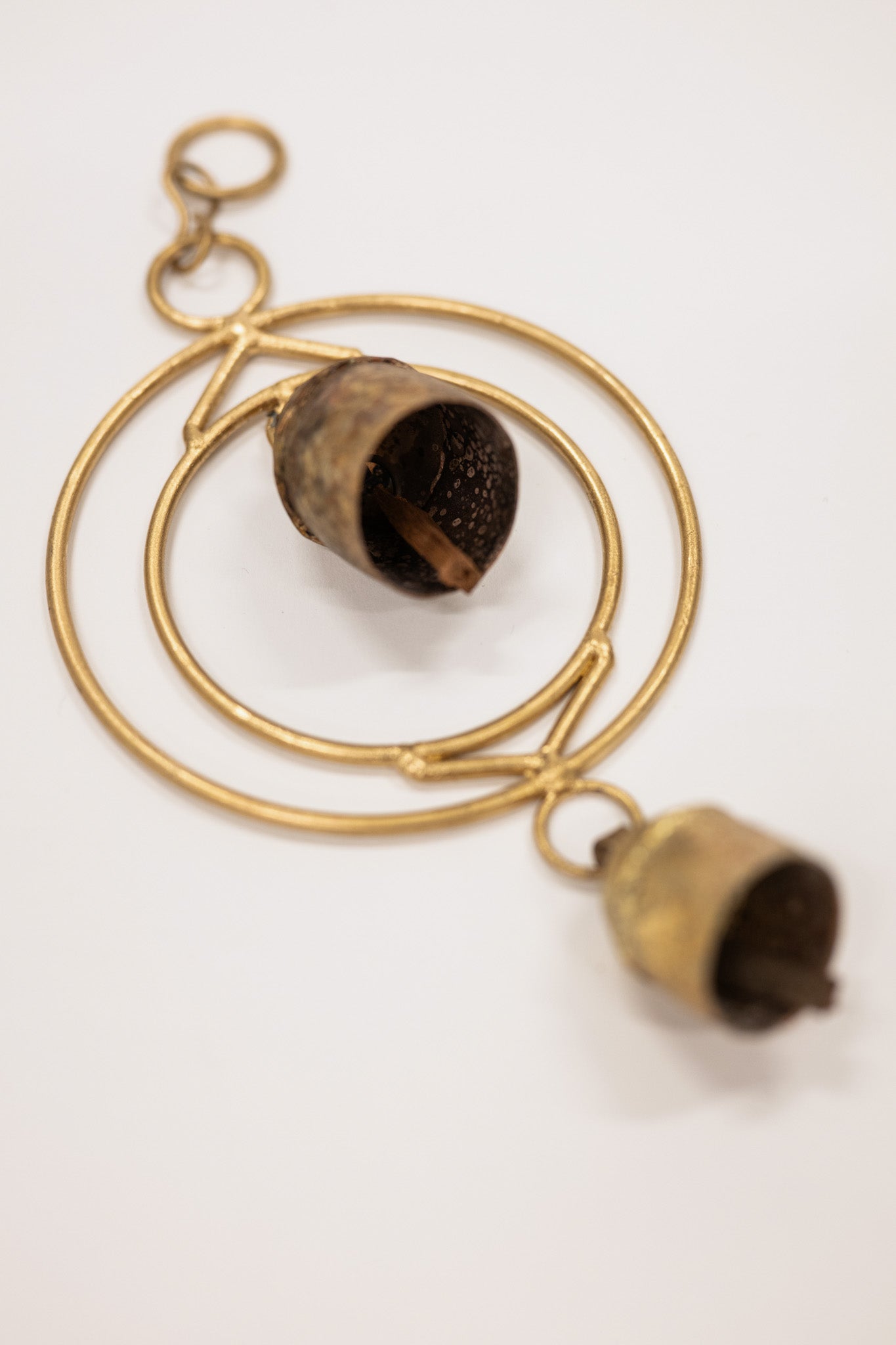 Gold circular pendant with chimes on a white background