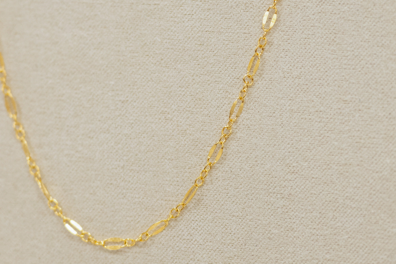 Gold chain necklace on a beige background