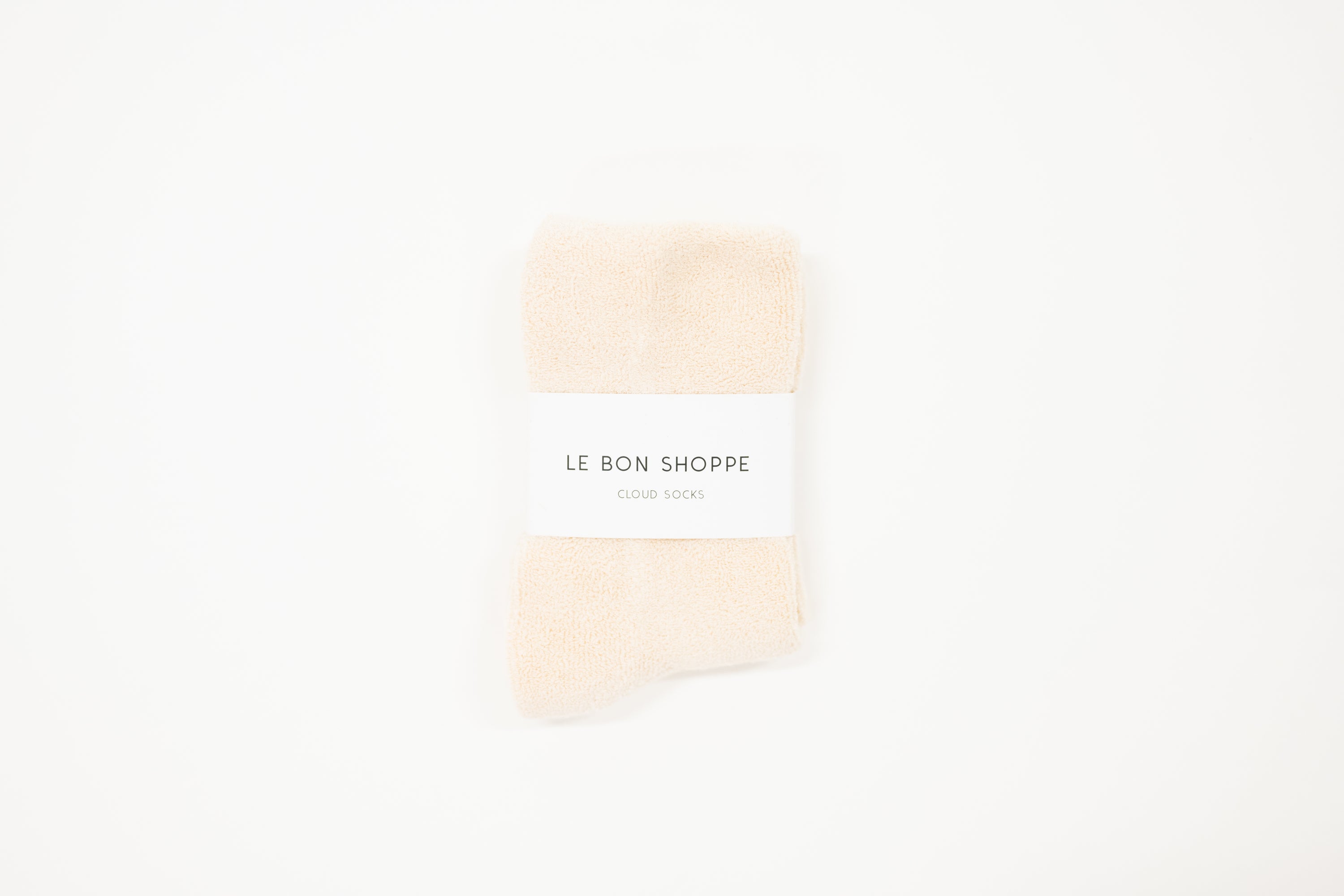 white cloud socks on a white surface, each with a label indicating the brand le bon shoppe