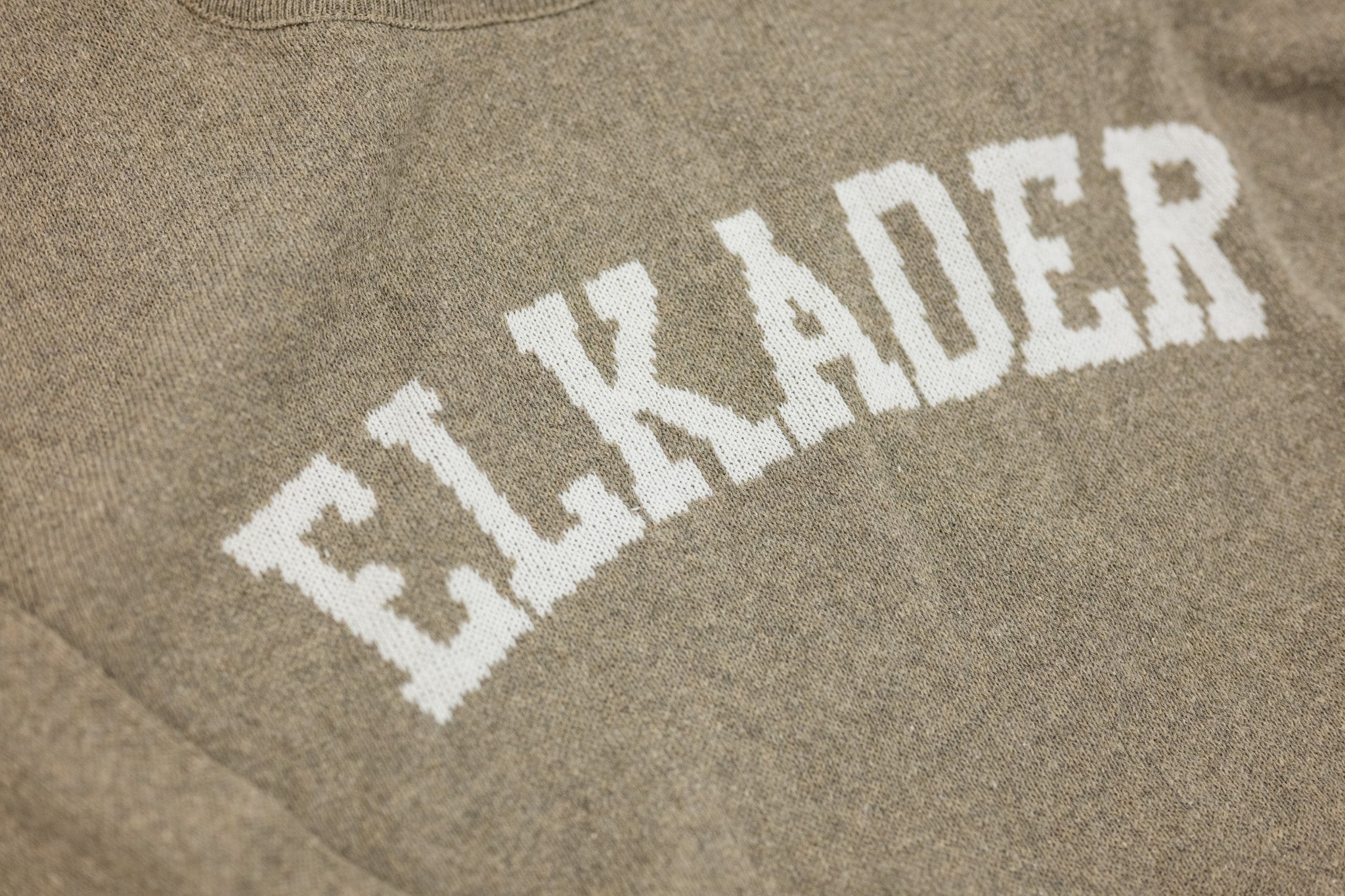 Text 'ELKADER' printed on a brown fabric background