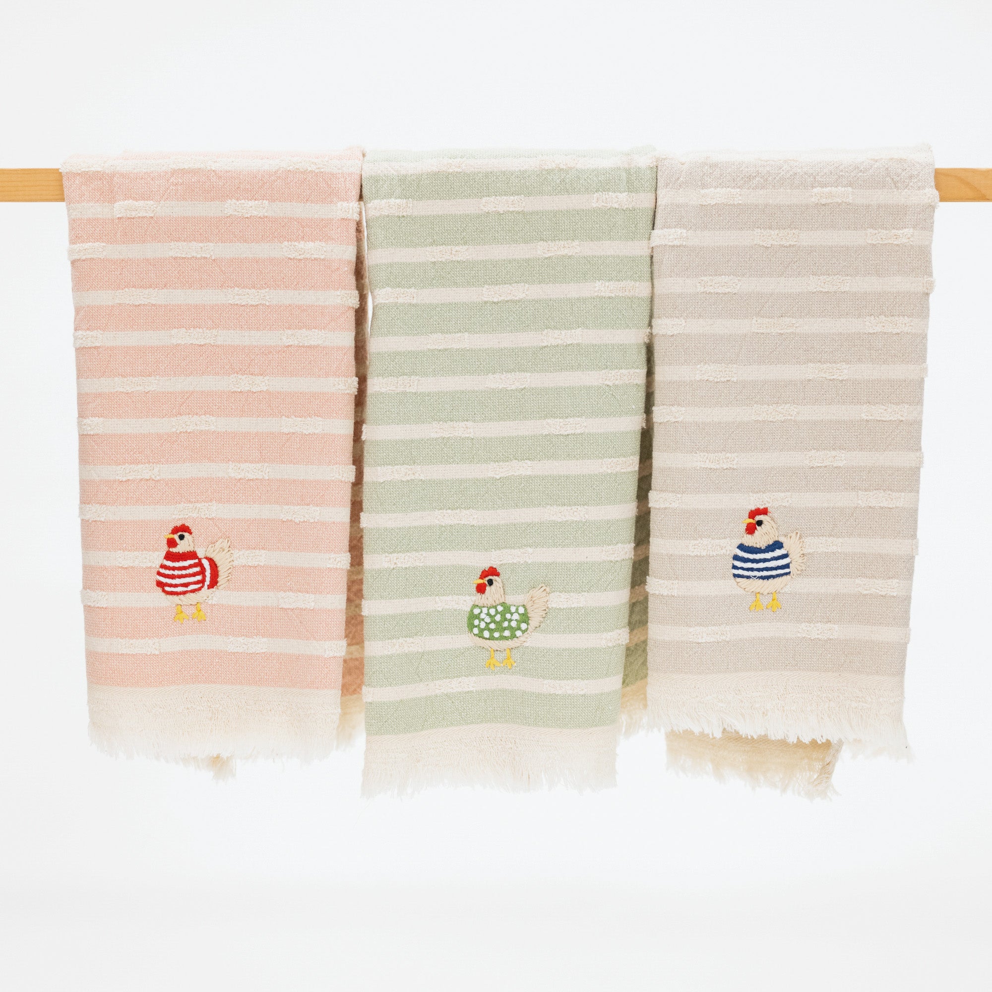 set of three kitchen towels with stripes and embroidered chickens. each chicken features a different sweater on the chicken