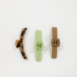 Three hair clips in brown, green, and beige on a white background