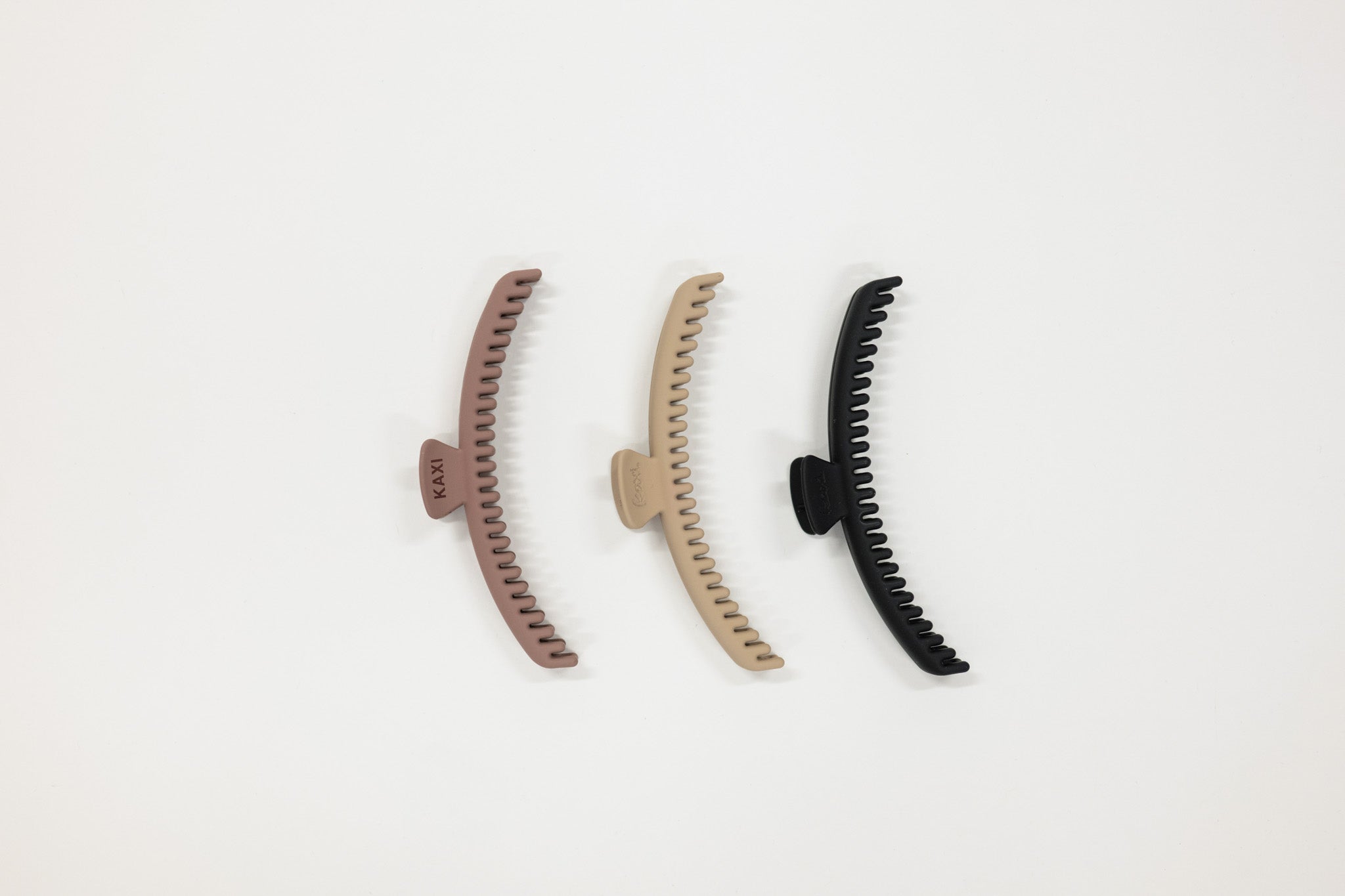 Three hair claws in brown, beige, and black on a light gray background