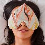 Person wearing a patterned eye mask on a soft surface