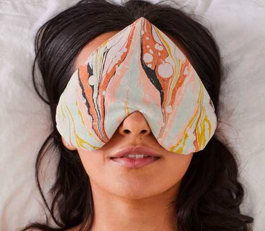 Person wearing a patterned eye mask on a soft surface
