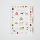 A spiral-bound watercolor painting guide book with a white cover, featuring various colorful watercolor illustrations of farm animals, a barn, a tractor, and a tree, alongside color swatches. The book is photographed flat against a clean white background.