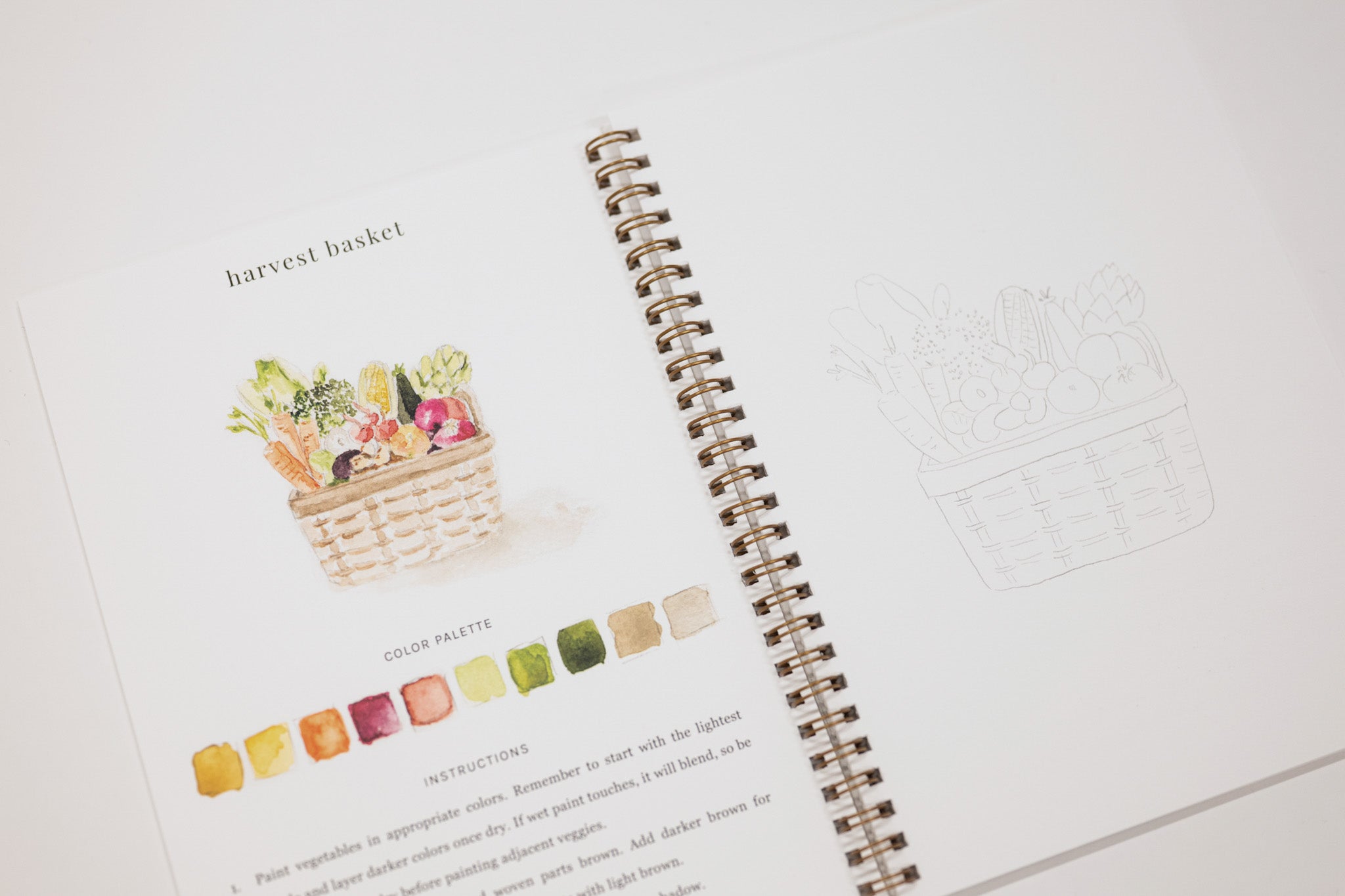 Spiral-bound notebook with a color swatch and illustration of a harvest basket on a white background