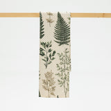 Towel with botanical design hanging on a wooden rack against a white background