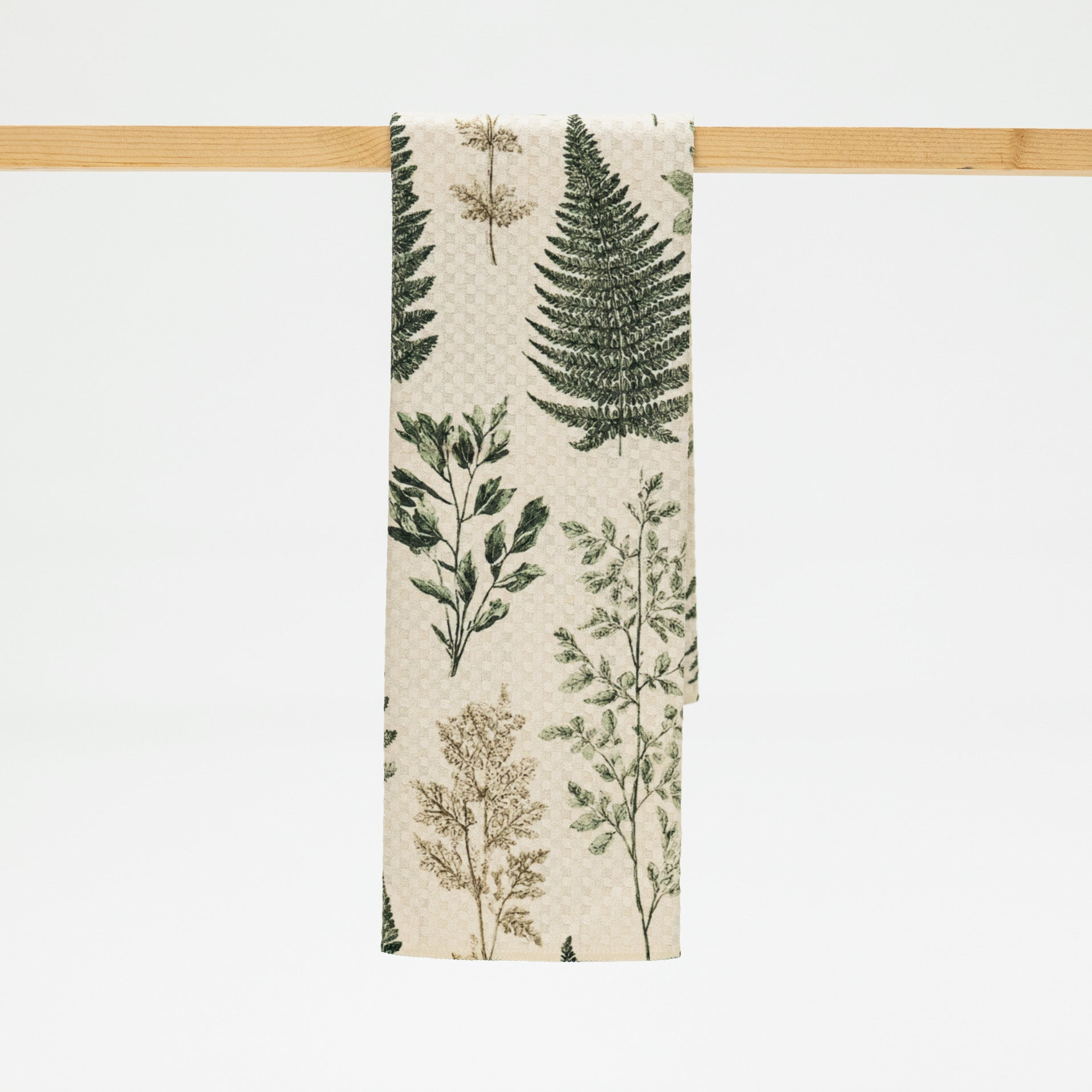 Towel with botanical design hanging on a wooden rack against a white background