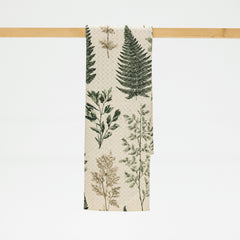 Towel with botanical design hanging on a wooden rack against a white background