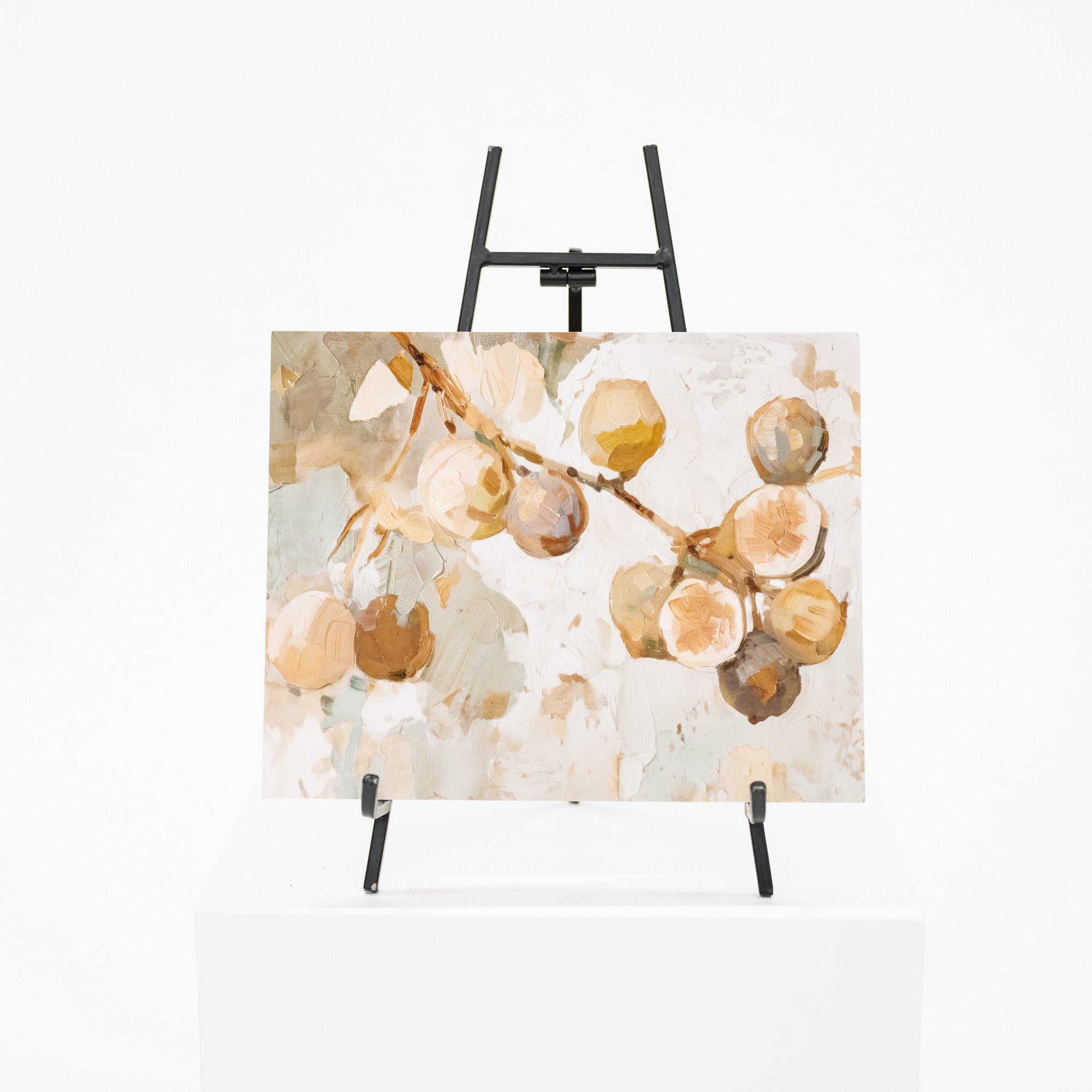 An abstract botanical painting of fig branches with beige, brown, and cream tones, displayed on a black easel stand over a white pedestal against a white background.