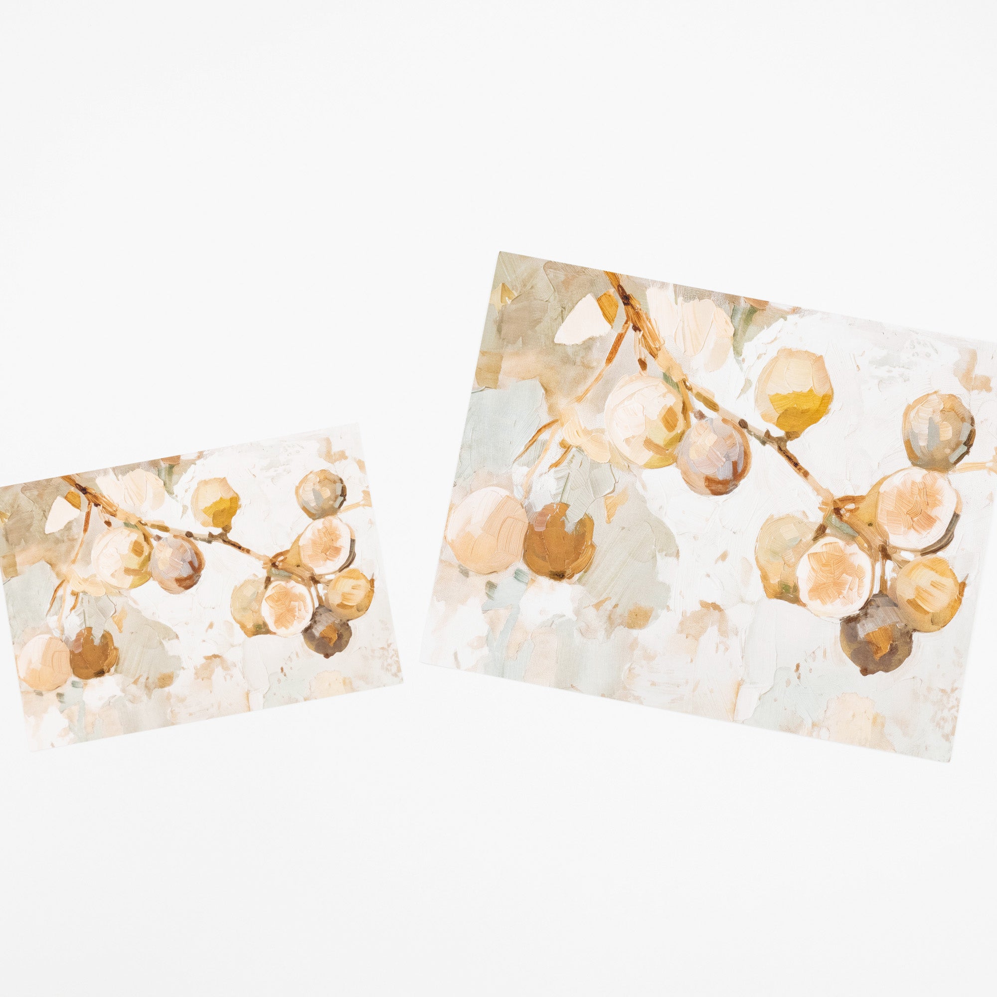 Two rectangular art prints or cards with a watercolor-style botanical design of pale peach and tan fruit on a soft off-white background, shown on a plain white backdrop.
