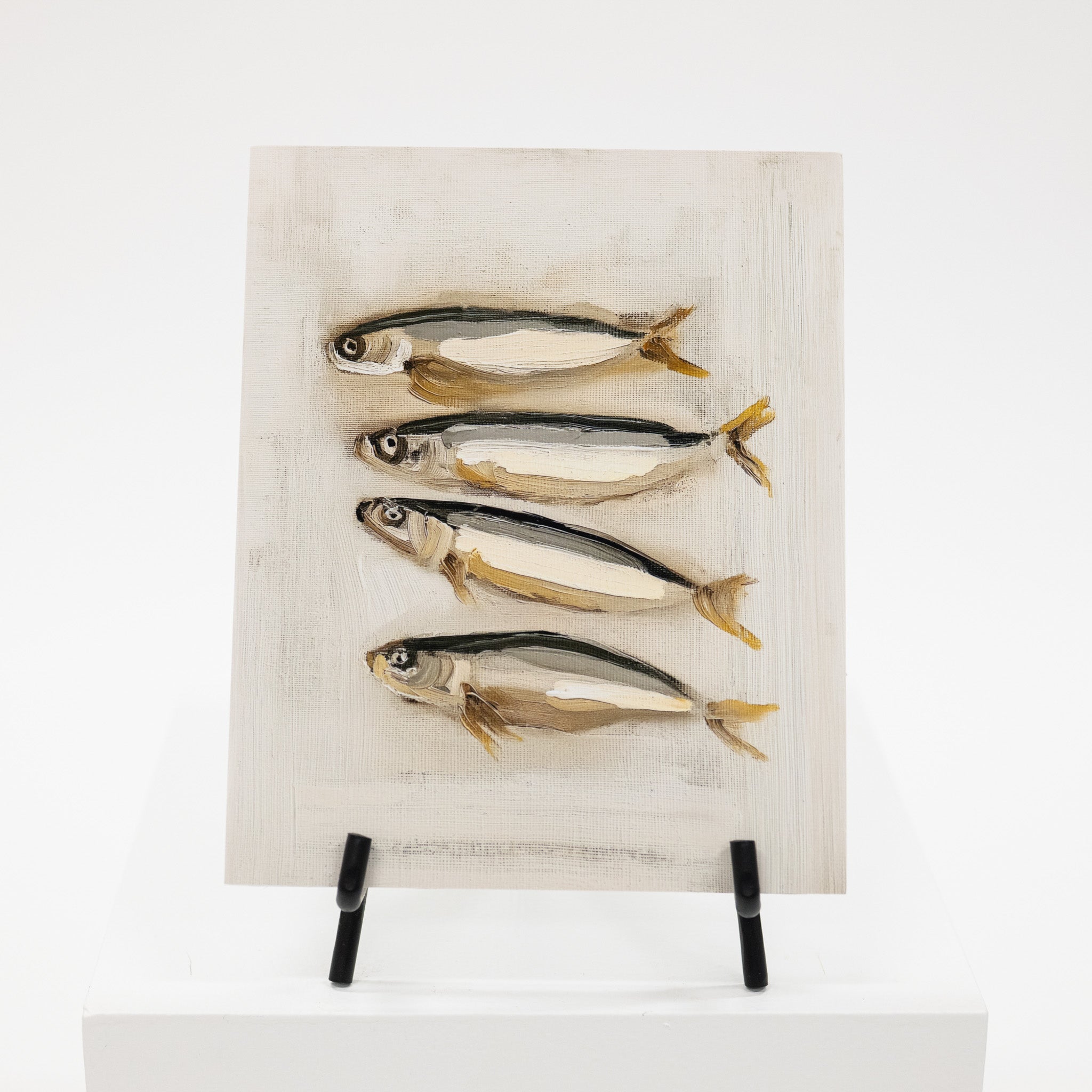 Four fish art print on a black easel.