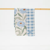 reversible kitchen towel with floral and checkered patterns hanging on a wooden rod.